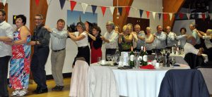 Image of members of Winslow Anglo French Twinning Association and visitors from Cours doing the Conga at the celebration dinner