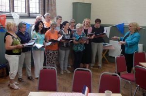Image of visitors from Cours singing to members of Winslow Anglo French Twinning Association during a trip to Winslow